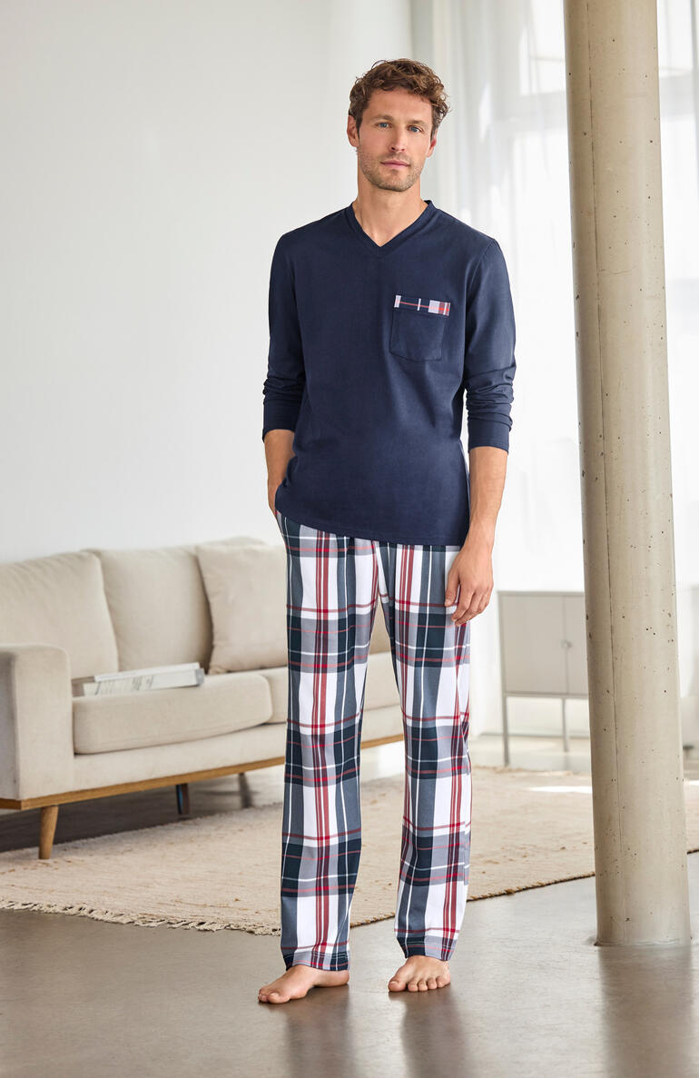 Homme en pyjama à carreaux bleus se tenant dans un salon.