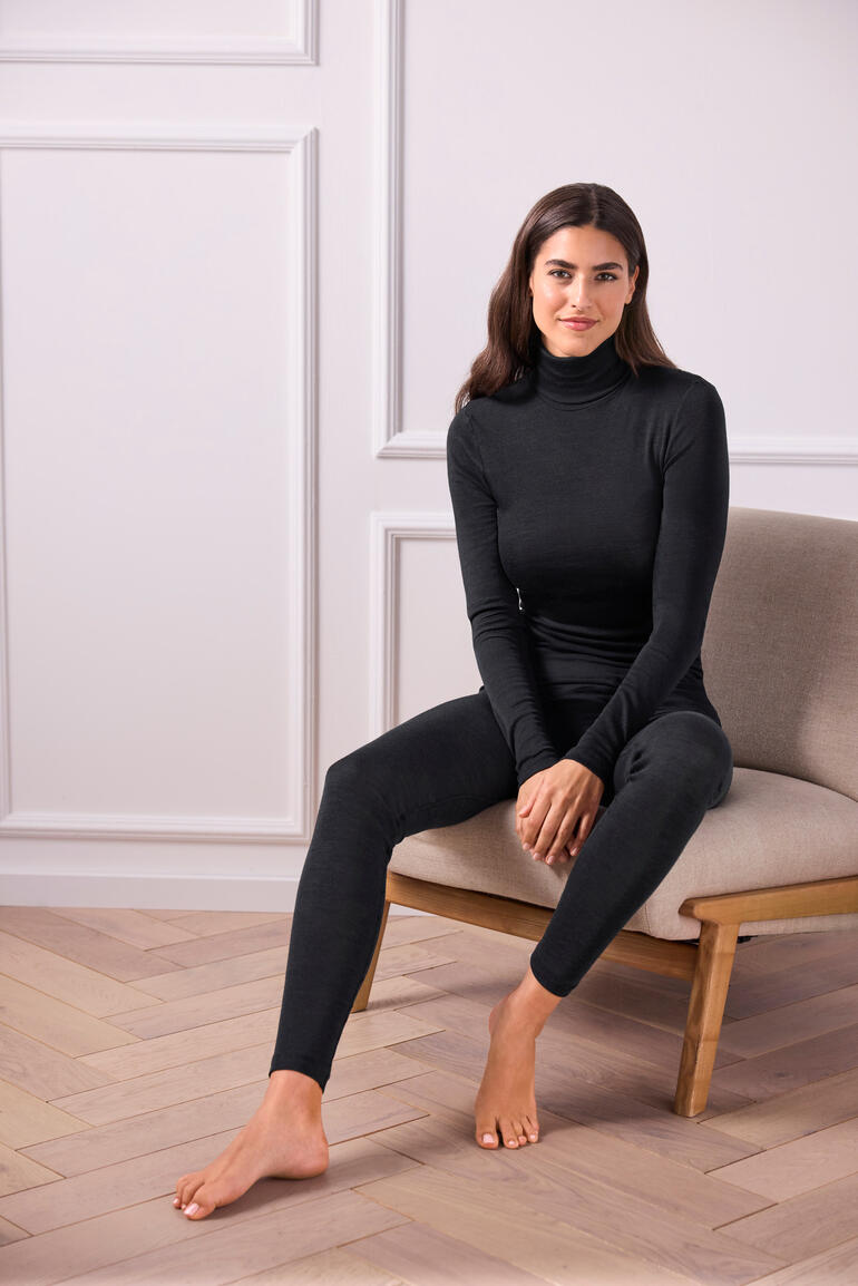 Pull col roulé noir pour femmes en laine et soie, taille 36-38, assise sur une chaise.
