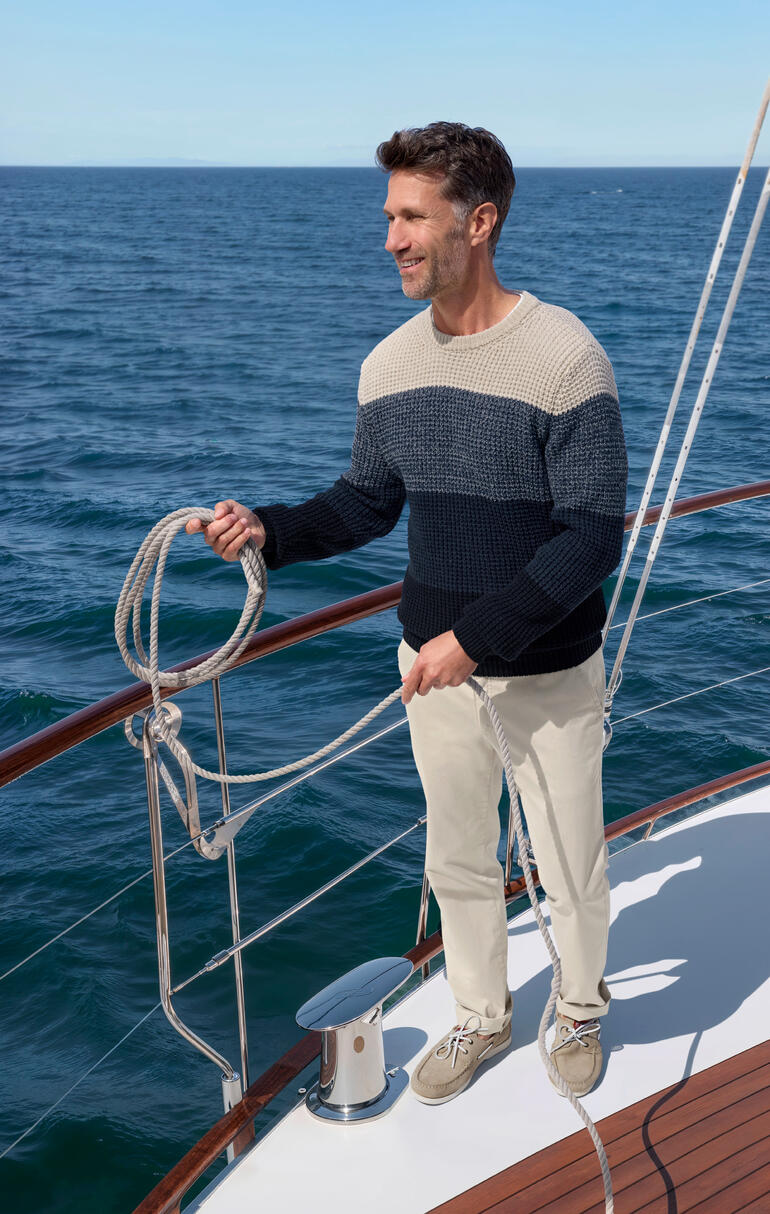 Homme portant un pull en perlfang sur un voilier au bord de la mer