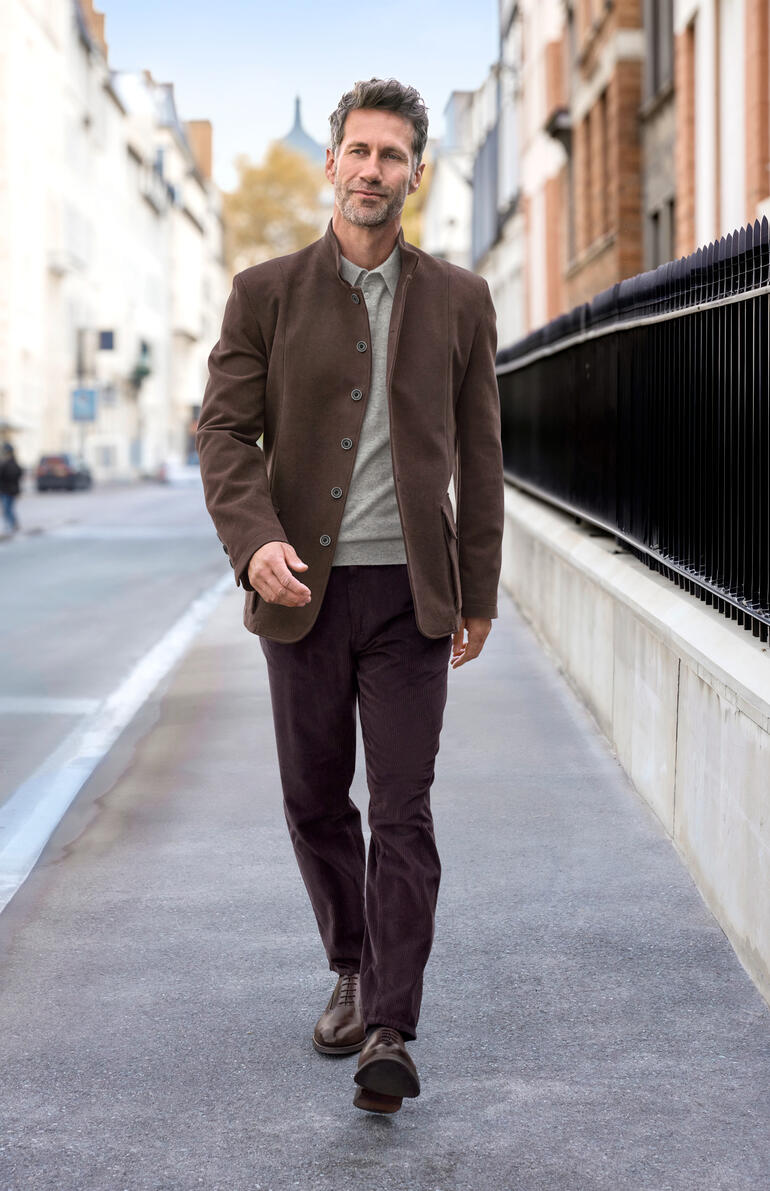 Homme en veste en moleskin marron marchant dans un environnement urbain