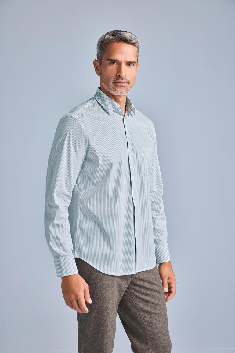 Homme debout dans une chemise en merino-soie bleu clair dans un studio.