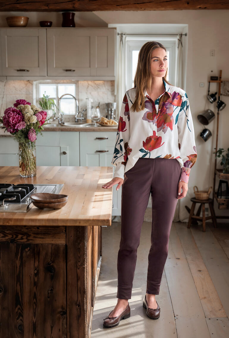 Femme portant une chemise en flanelle florale se tient dans une cuisine moderne.