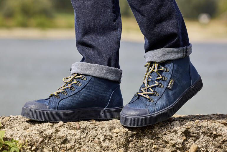 Un jeune homme portant des sneakers Cordura navy avec un jean retroussé