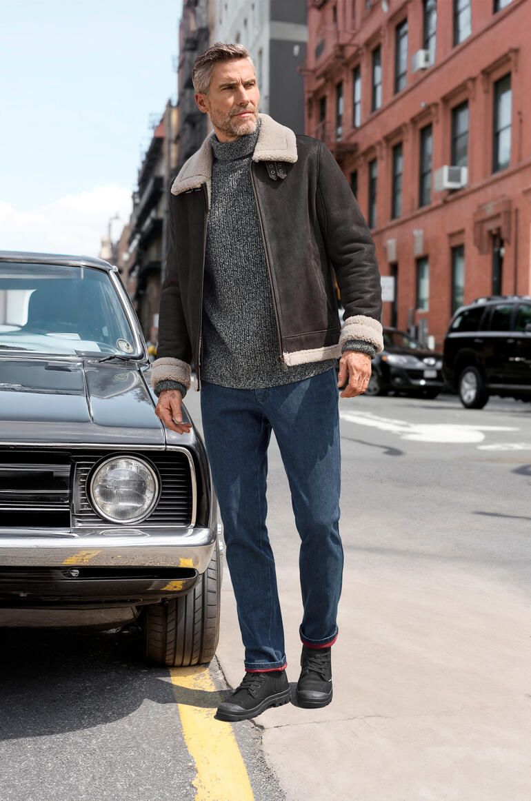 Homme en veste de pilote en agneau se tient à côté d'une voiture classique