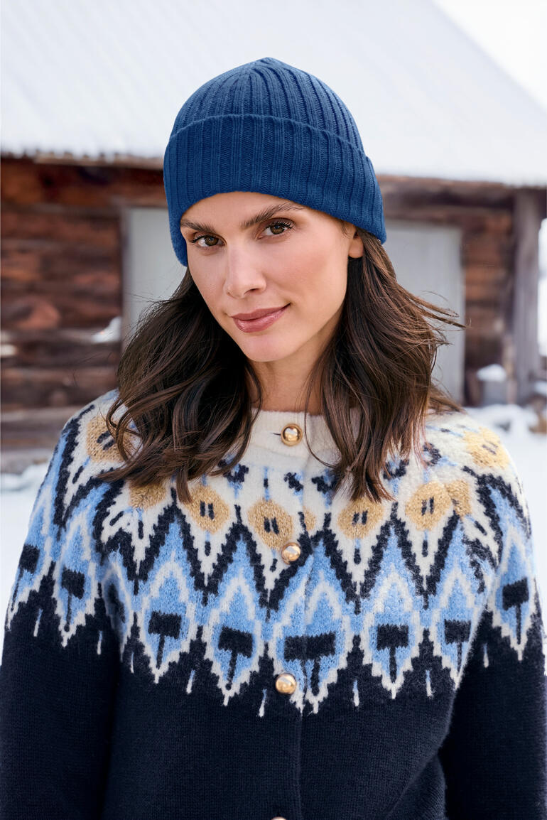 Femme portant un bonnet de pêcheur en cachemire bleu et une veste tricotée.