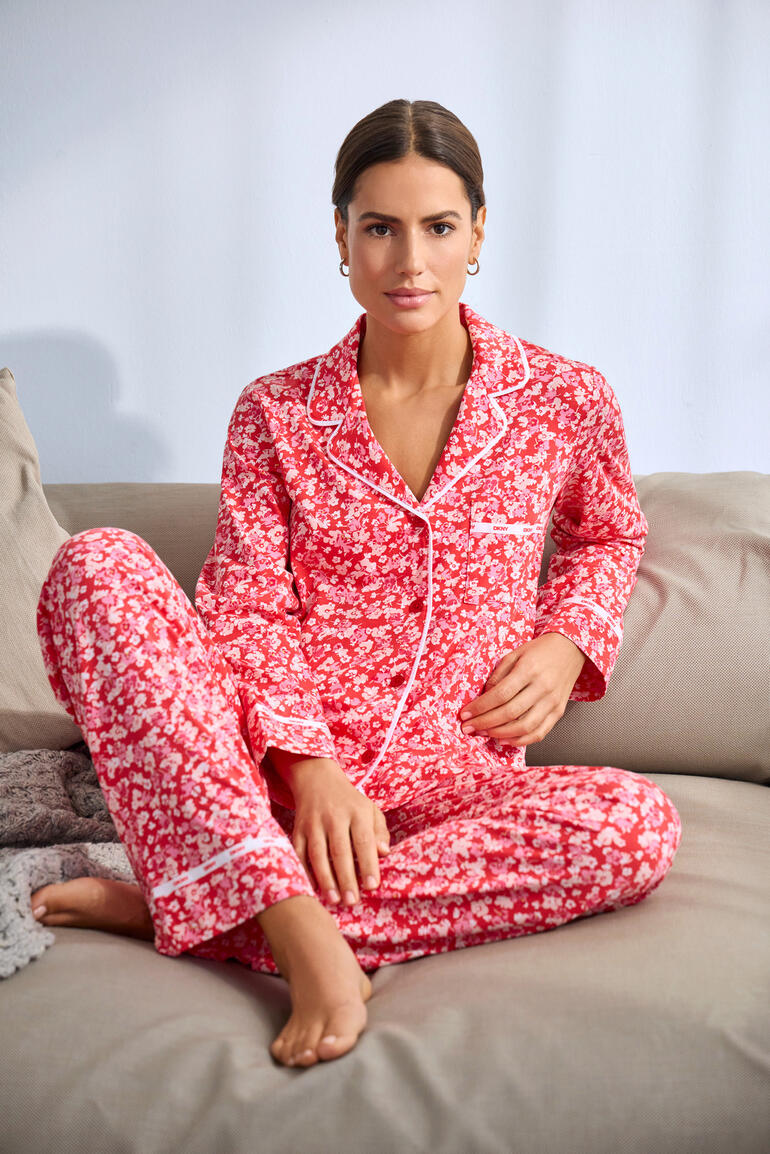 Pyjama imprimé fleurs DKNY en rouge, modèle assis sur le canapé.