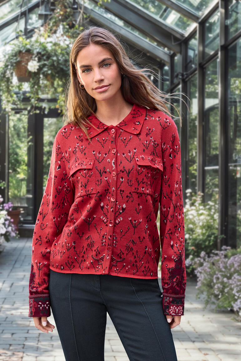 Femme en blouse en jacquard rouge avec motif floral dans une serre.