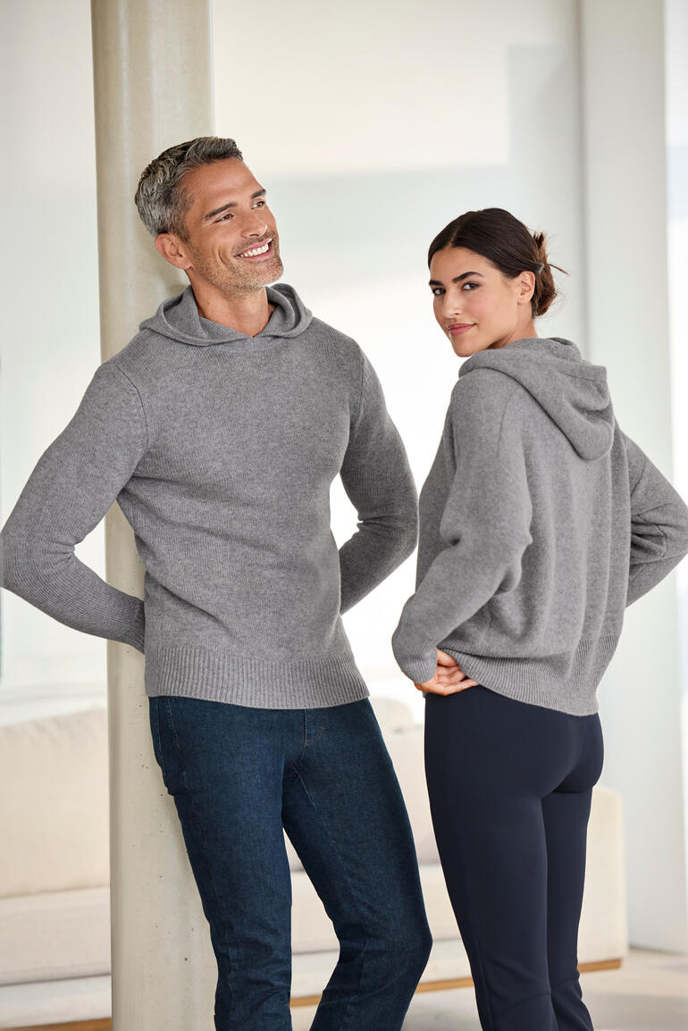 Couple portant un hoodie D en cachemire bouilli gris dans un salon moderne.