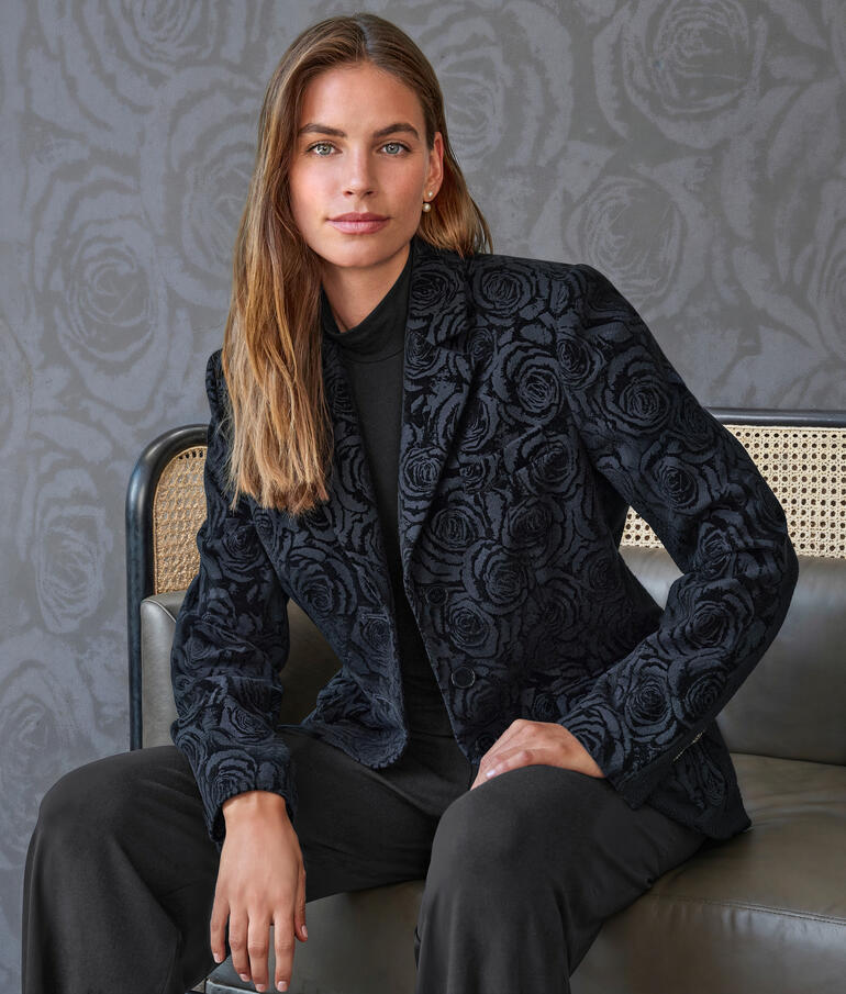 Femme en blazer brodé de fleurs regardant droit dans l'objectif.