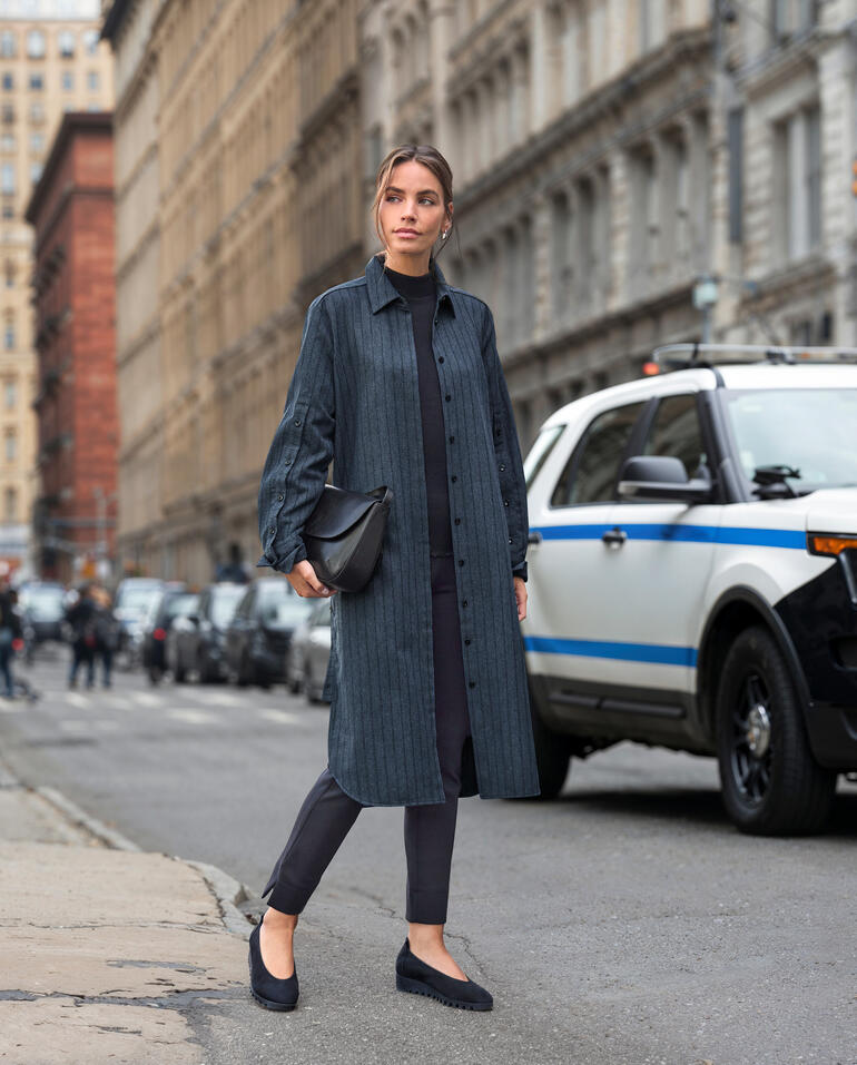 Femme en robe longue à rayures dans la rue de la ville.