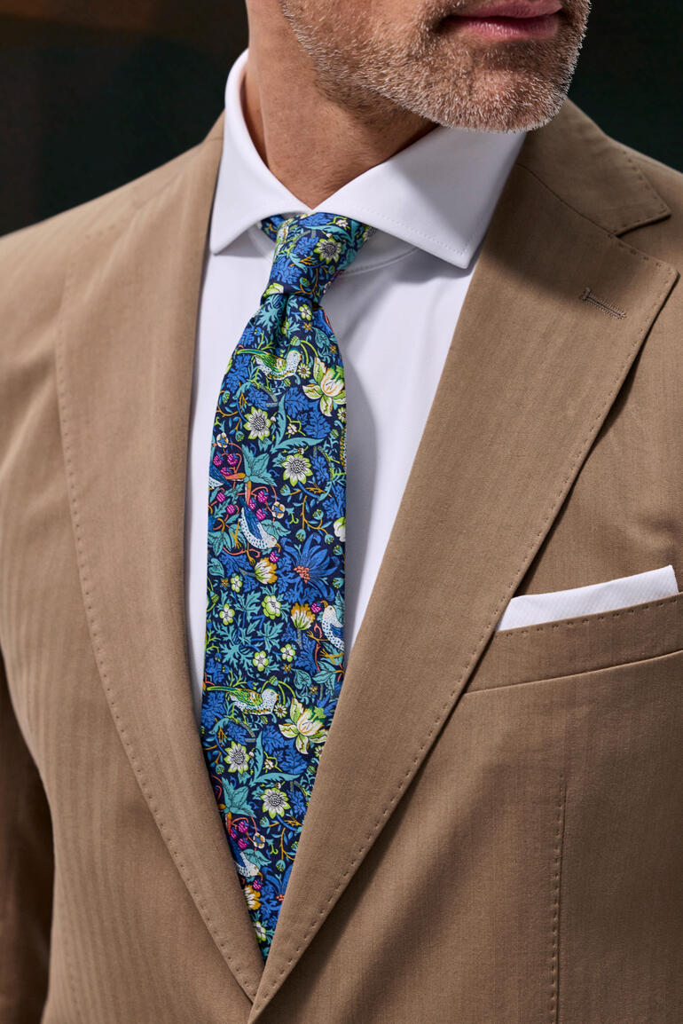 Homme portant une veste en lyocell et coton clair avec une cravate colorée et une chemise blanche.