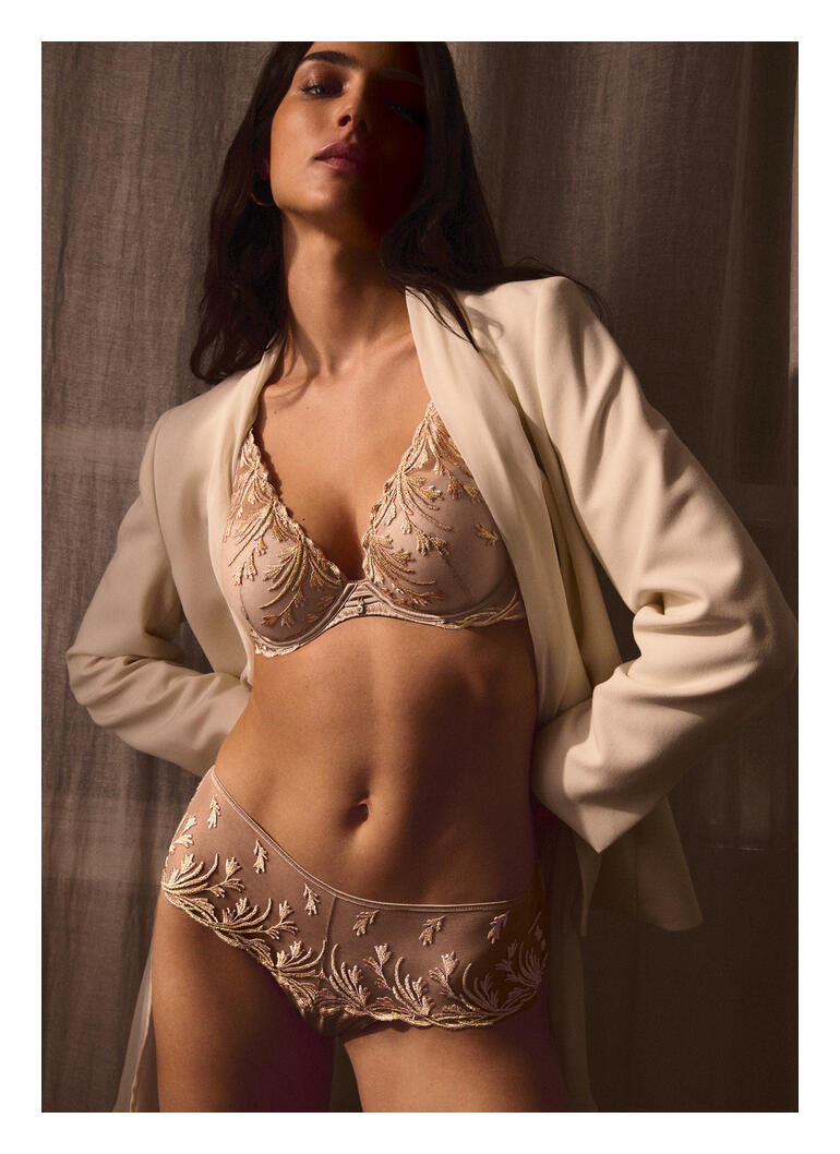 Soutien-gorge pour femme avec des ornements délicats en couleur sable sur un fond neutre.