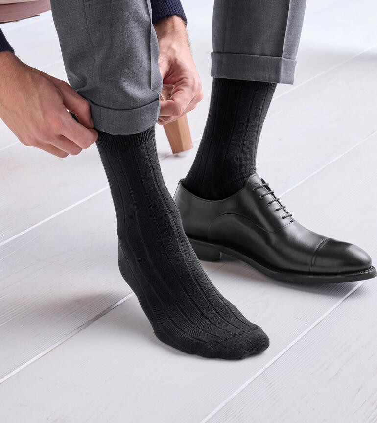 Homme enfile des chaussettes en alpaga grises