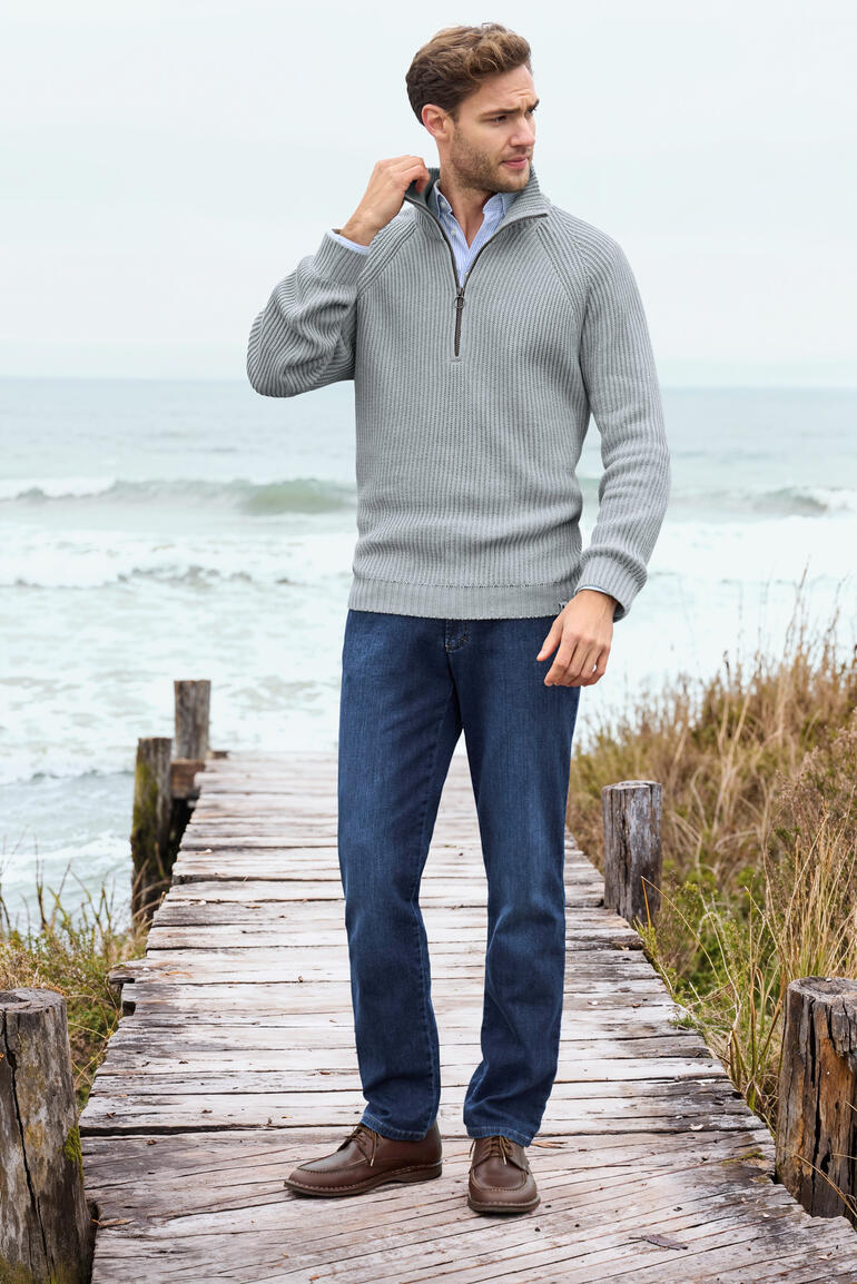 Homme portant un pull gris sur la plage.