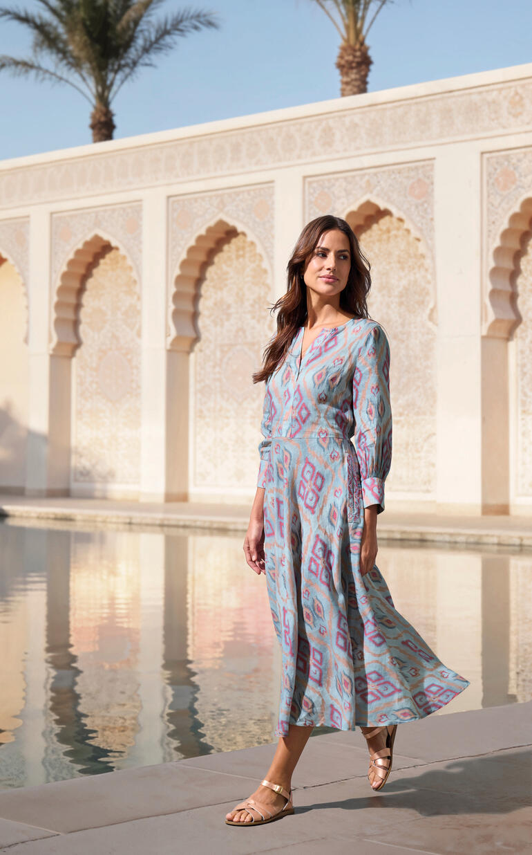 Femme en robe Ikat colorée à côté d'une piscine en plein air.