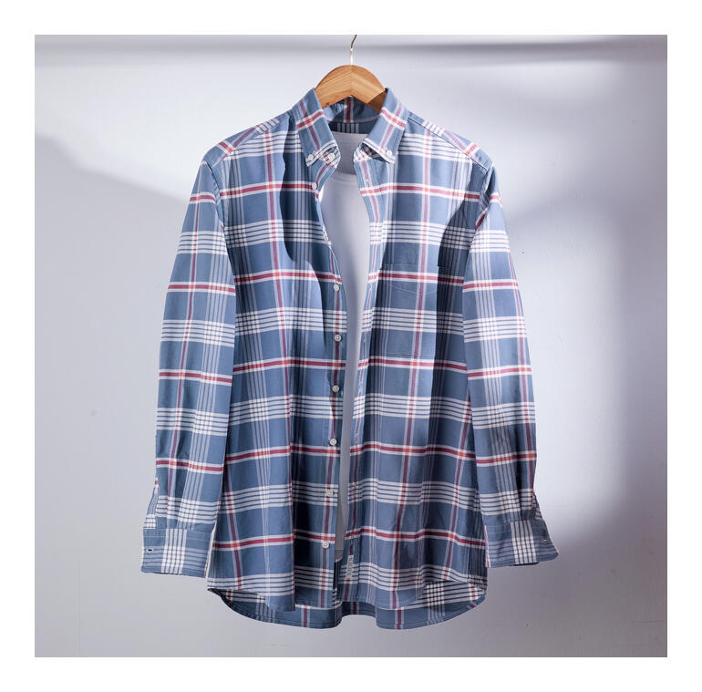 Chemise à carreaux en tons de bleu, accrochée de manière décontractée sur un cintre en bois