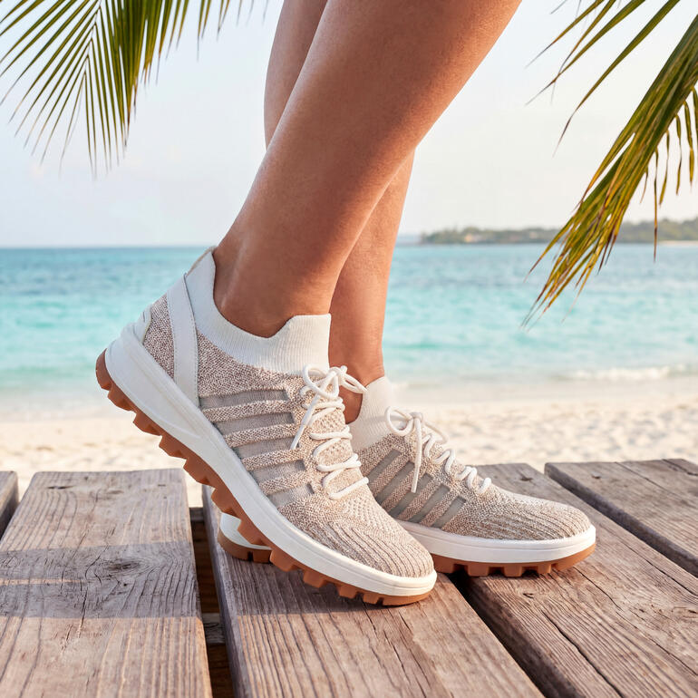 Pieds dans des baskets à lacets Bernie Mev Knit blanches, taille 36, sur la plage.