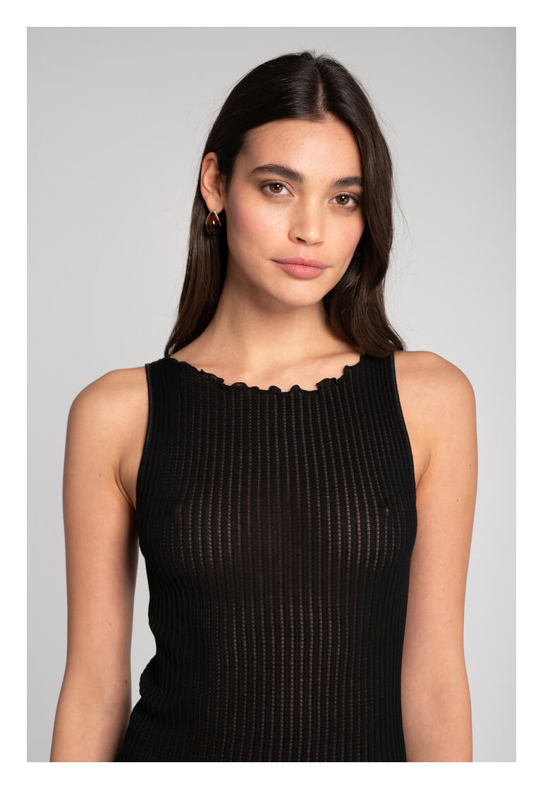 Femme portant un top en côtes noires Oscalito avec bord ondulé et boucles d'oreilles