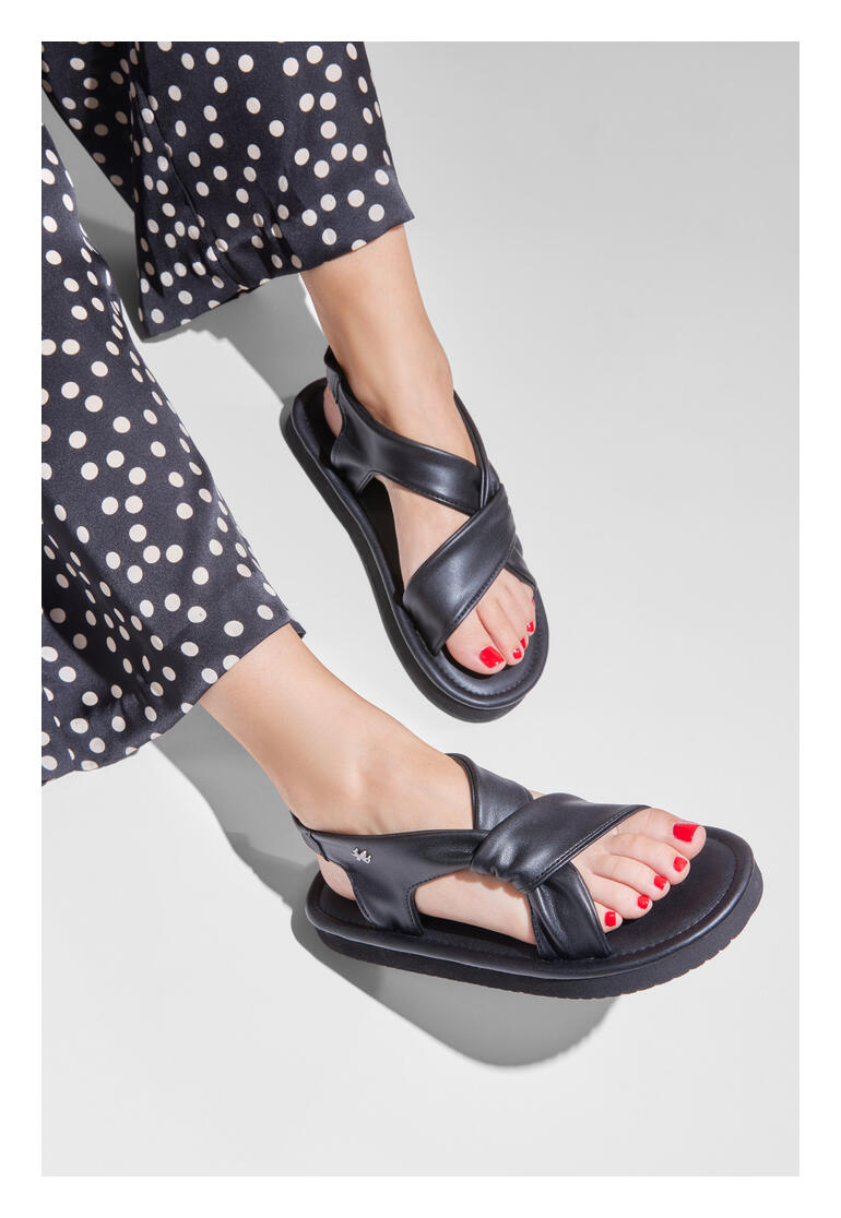 Pieds d'une femme dans des sandales flip-flop Ultralight noires avec vernis à ongles