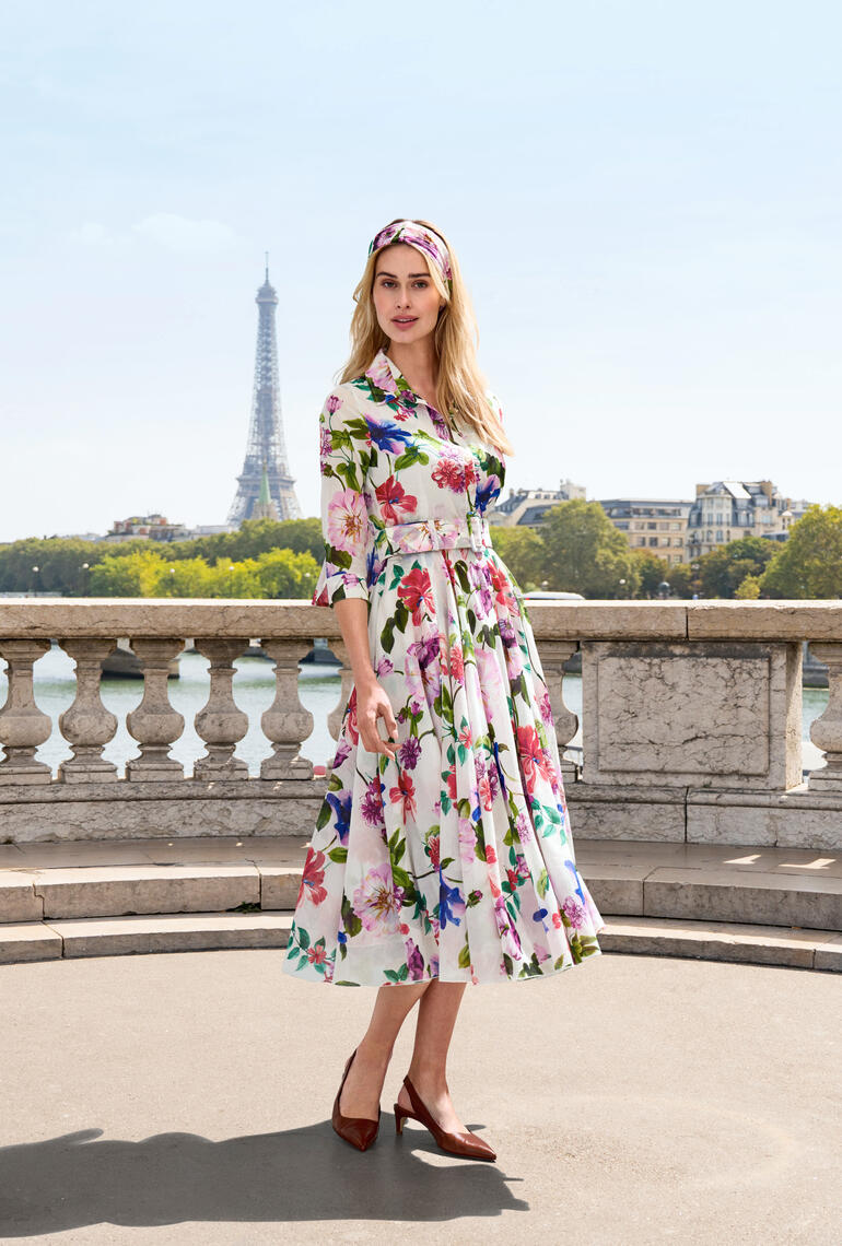 Femme portant une robe à motif d'hibiscus, posant devant la Tour Eiffel à Paris.