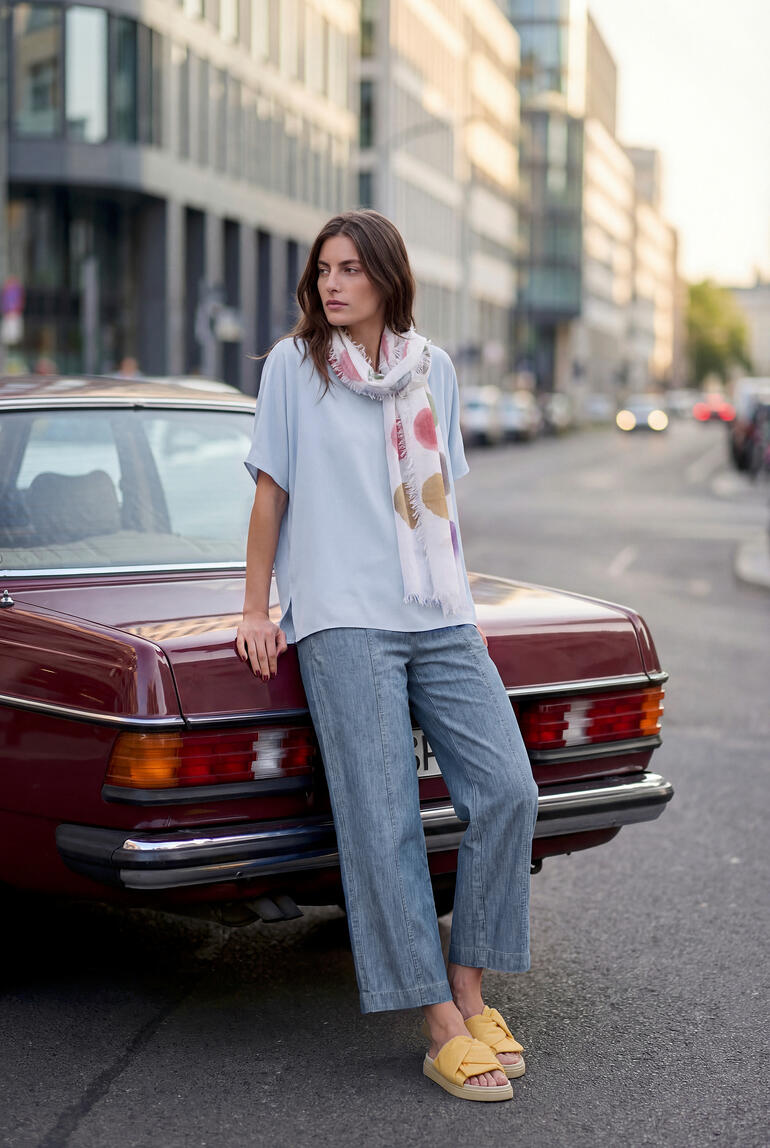 Femme en t-shirt ciel et tenue décontractée à côté d'une voiture