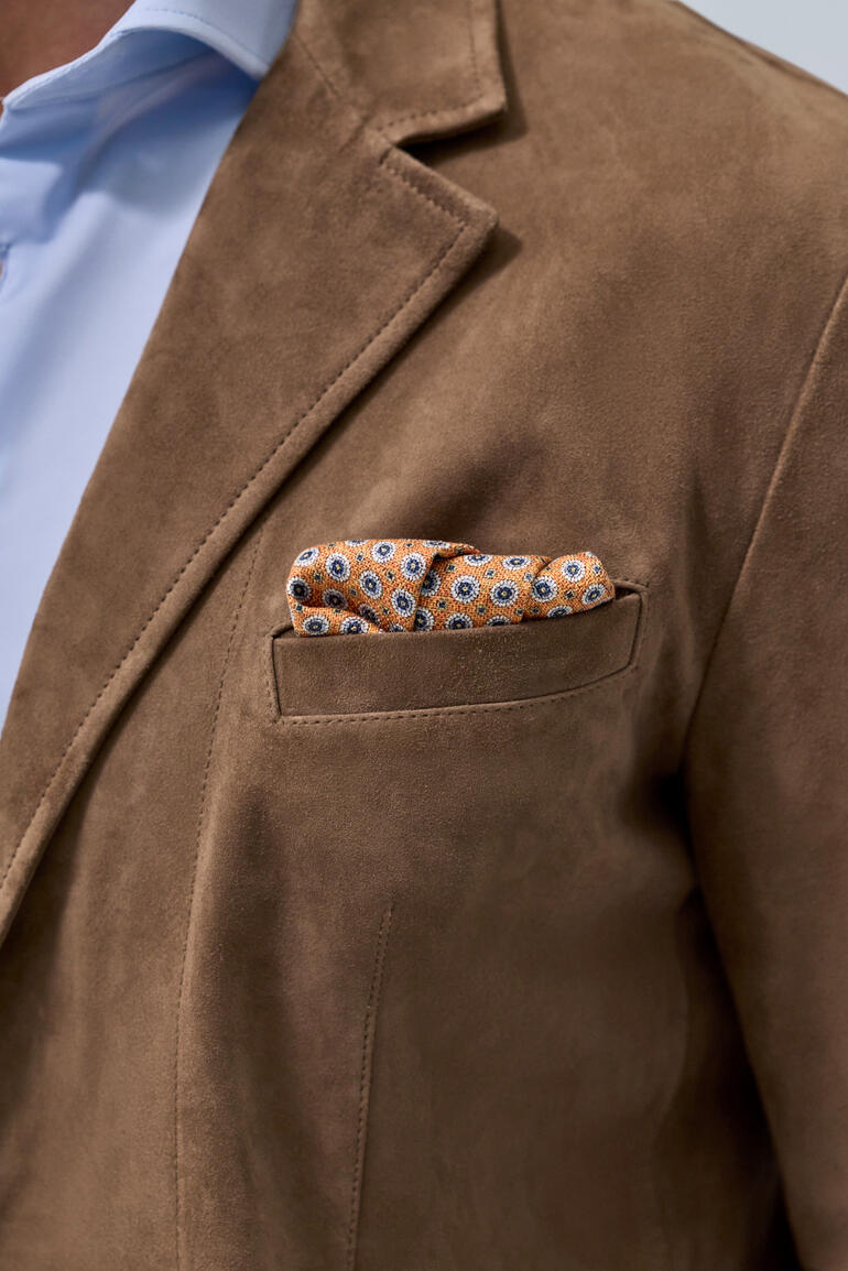 Veste en cuir lavable en taupe, taille 48, avec un mouchoir orange dans la poche poitrine.