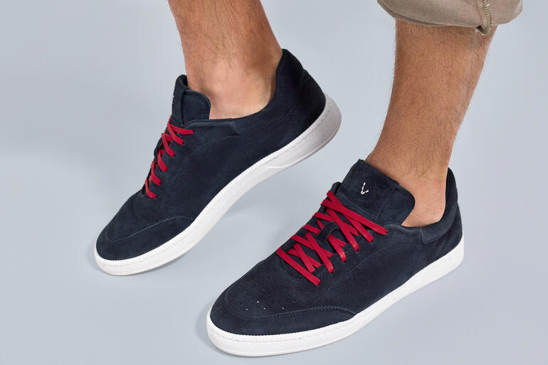 Baskets d'été navy avec des lacets rouges, posées sur un fond gris.