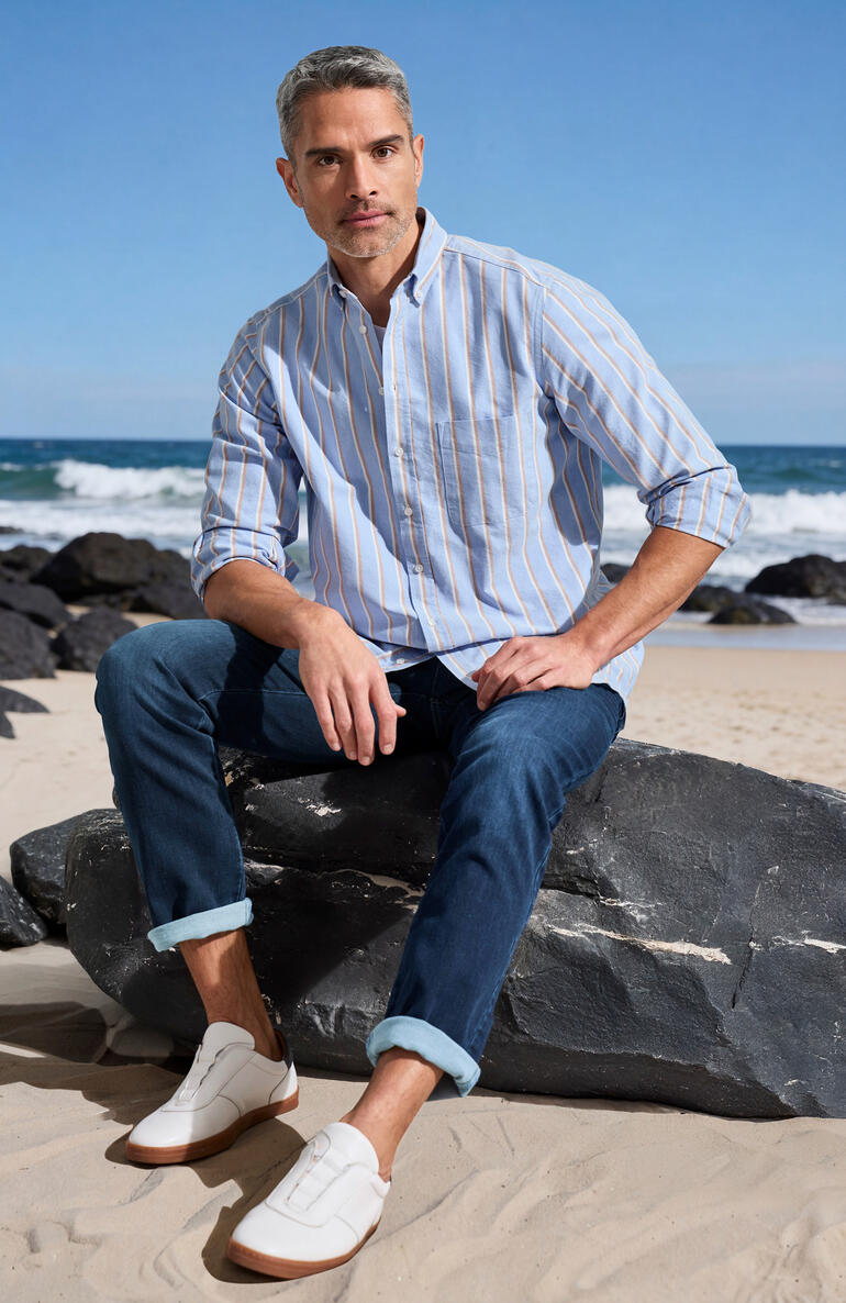 Homme portant une chemise à carreaux sur la plage entre les rochers.