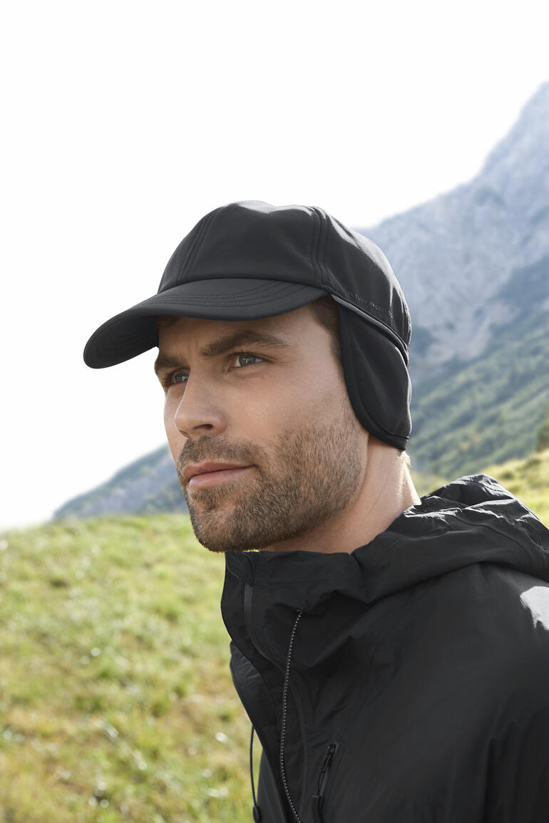 Homme portant une casquette softshell noire et une veste en plein air.