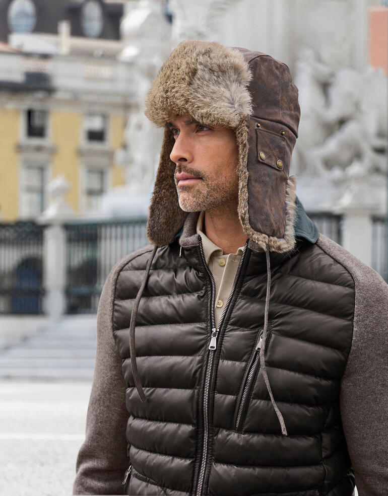 Chapka Stetson Homme portant un chapeau en peau de mouton brun avec des protège-oreilles.