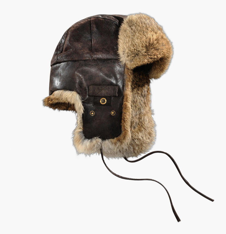 Chapeau en peau de mouton brun avec des protège-oreilles sur fond blanc.