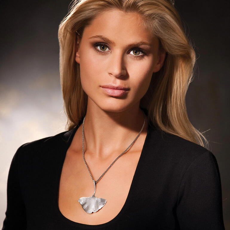 Femme portant un collier en ginkgo argenté en regardant sur le côté.