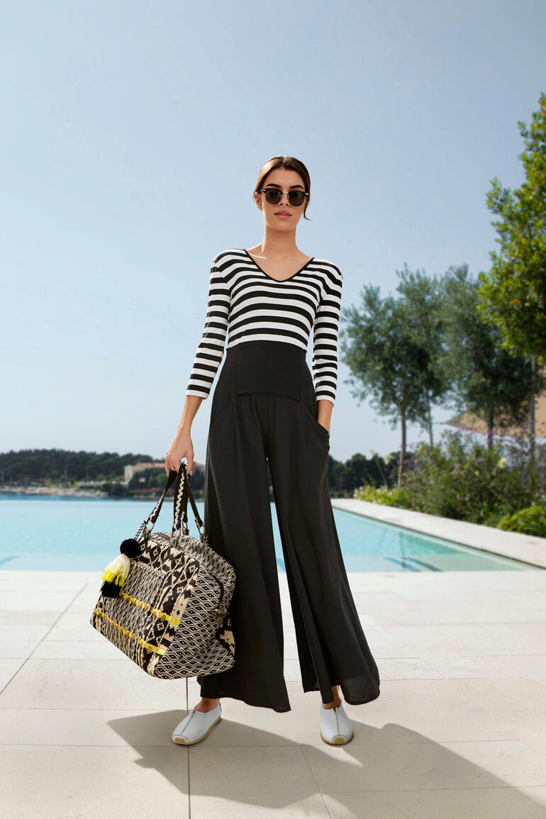 Sac week-end Manju Smitten Femme portant une jupe large Ibiza rayée et tenant un sac.