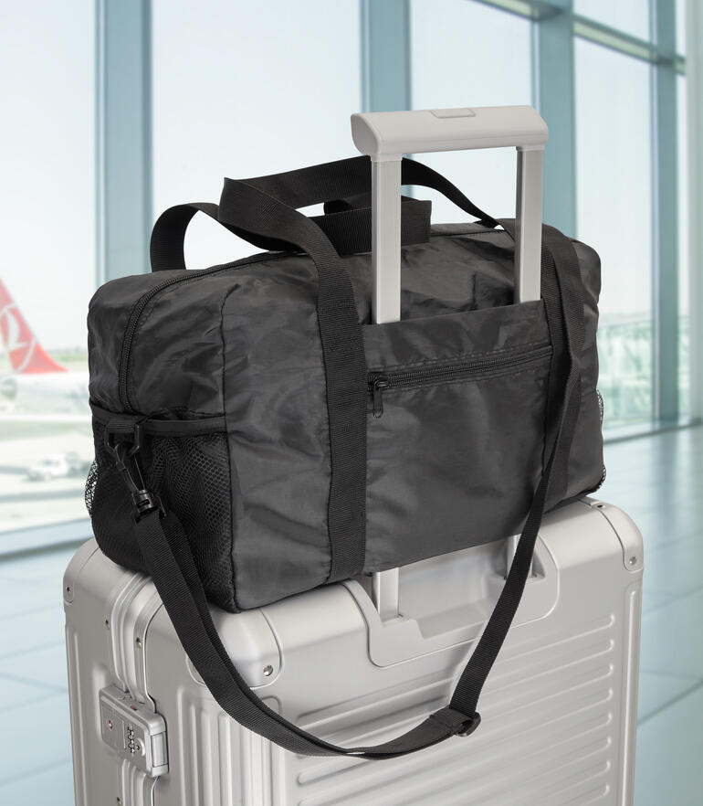 Sac de voyage pliable exclusif sur une valise à l'aéroport.