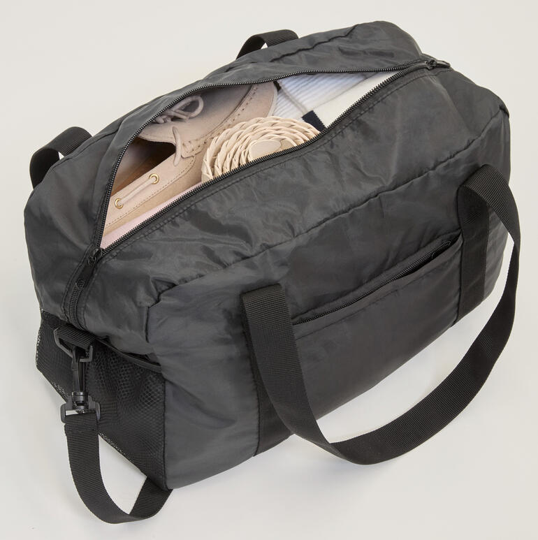 Sac de voyage pliable ouvert avec des chaussures et d'autres articles.