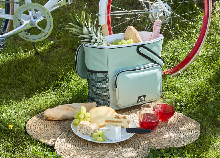 Sac isotherme de panier à vélo confortable avec des aliments sur l'herbe.