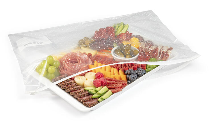 Plat avec divers morceaux de fruits et de charcuterie dans un emballage.