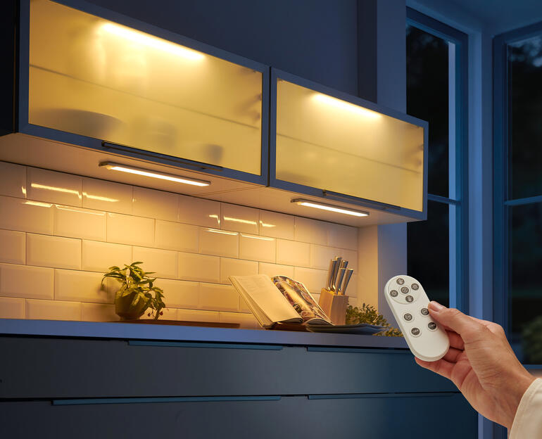 Barre lumineuse à batterie avec télécommande au-dessus d'un plan de travail.