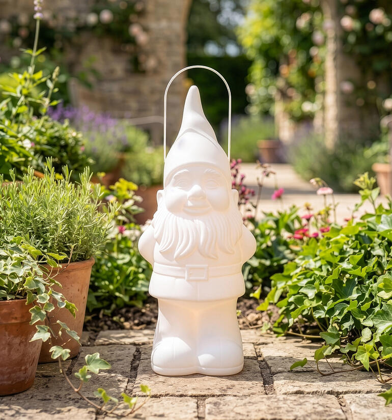 Nain de jardin blanc avec un seau dans un environnement fleuri