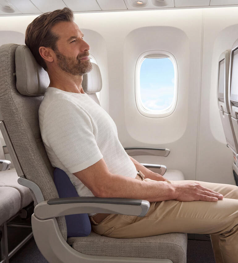 Homme assis dans un avion avec un coussin de voyage pour le soutien du dos.