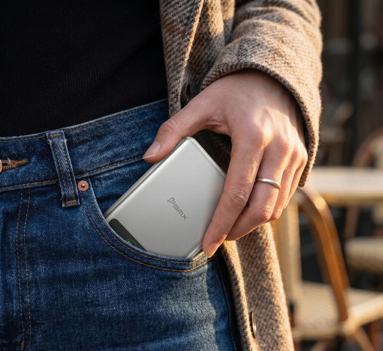 Une main mettant une power bank argentée dans une poche.