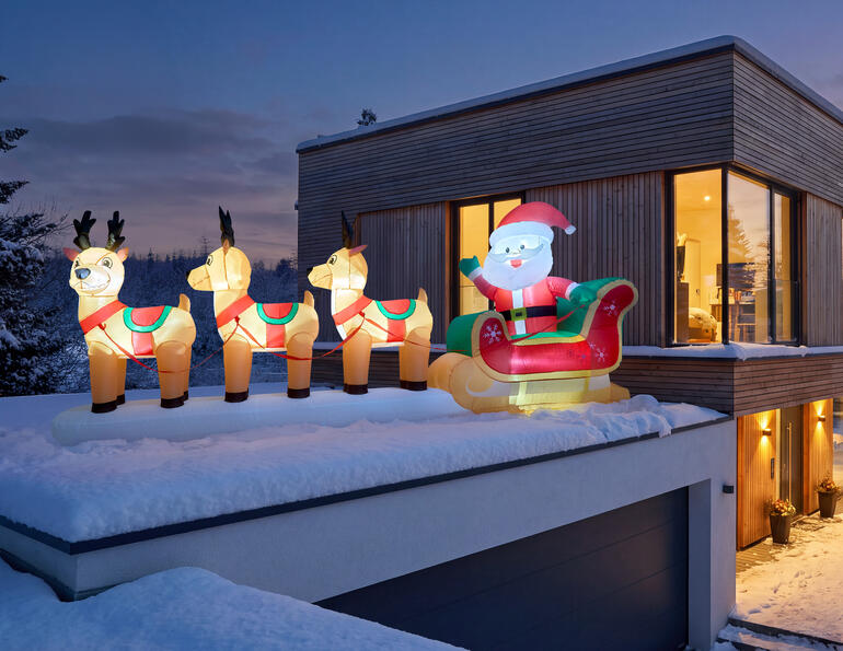 Sapin de Noël gonflable avec le Père Noël sur le toit d'une maison moderne.