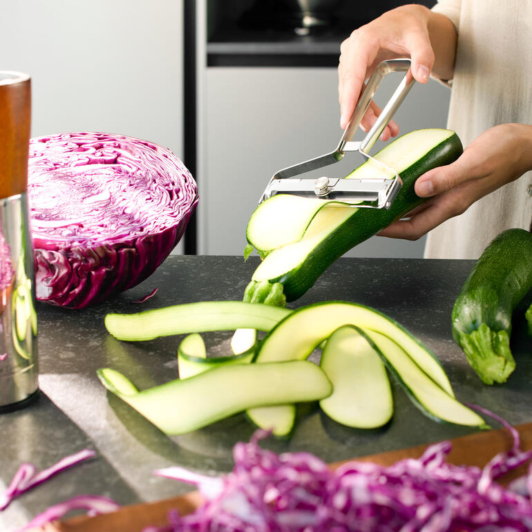 Éplucheur Vario XL pelant des courgettes dans une cuisine moderne.