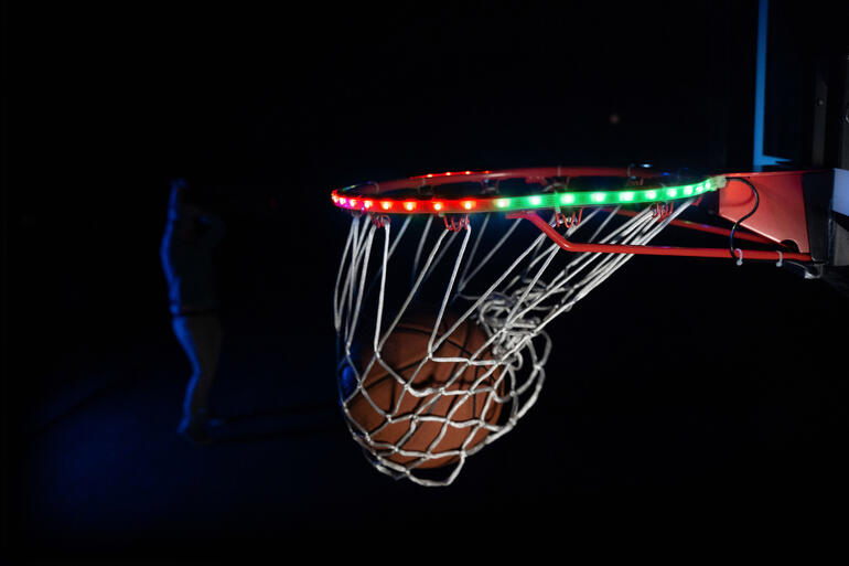 Gros plan du panier de basket avec éclairage LED et une balle à proximité.