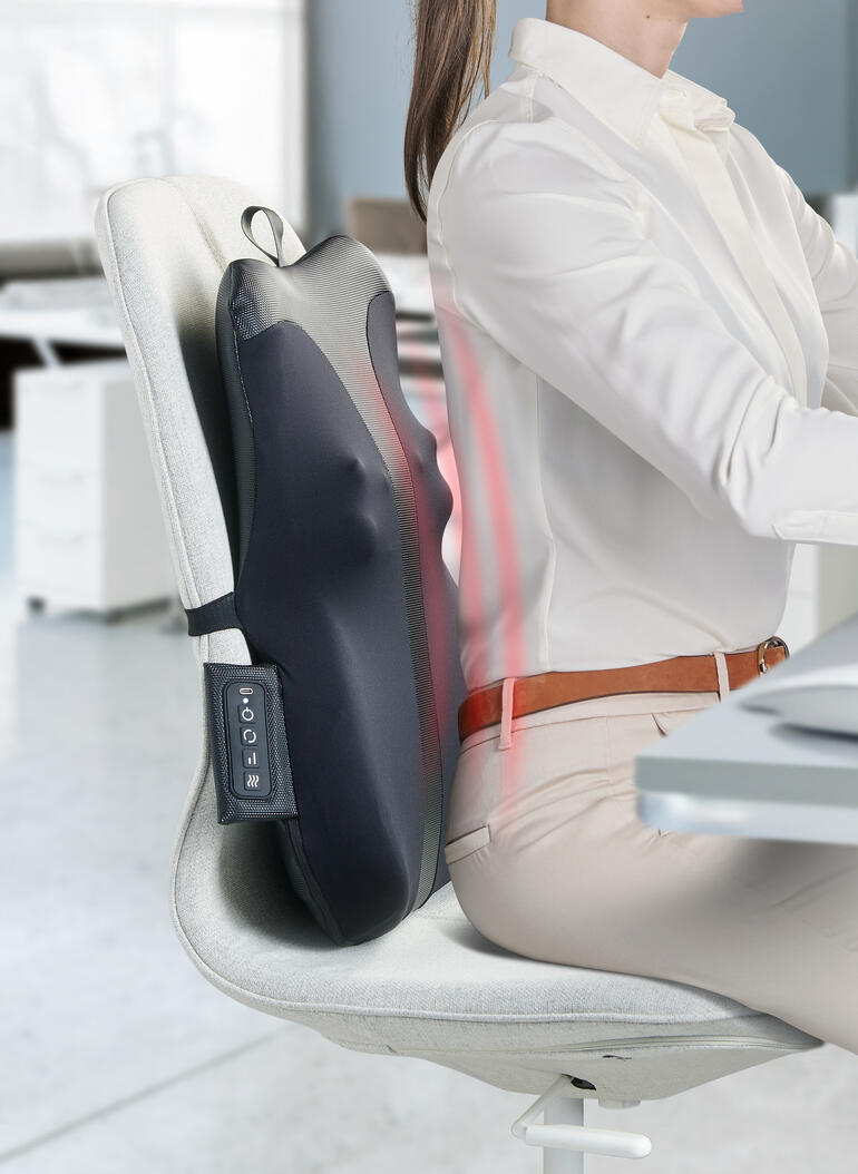 Appareil de massage du dos fixé à une chaise de bureau pendant qu'une personne travaille.