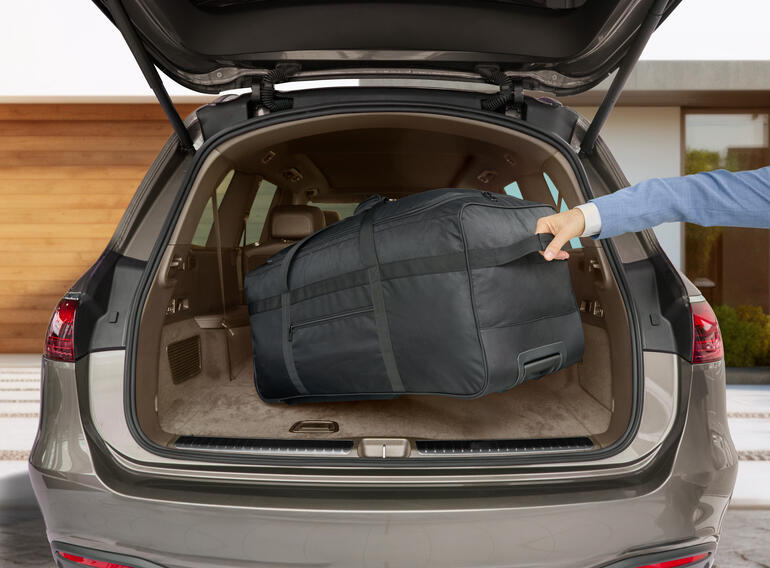 Le sac de voyage noir est chargé dans le coffre d'une voiture.