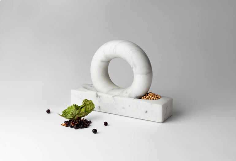 Mortier en marbre blanc avec un design en forme d'anneau et des épices dessus.