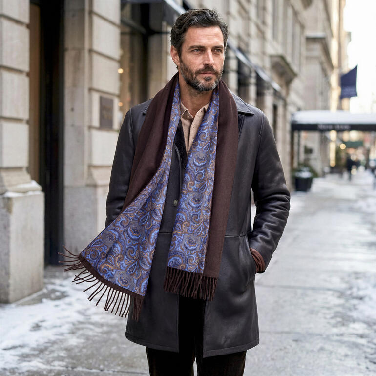 Homme avec une écharpe en soie à motif paisley et un manteau brun en ville.