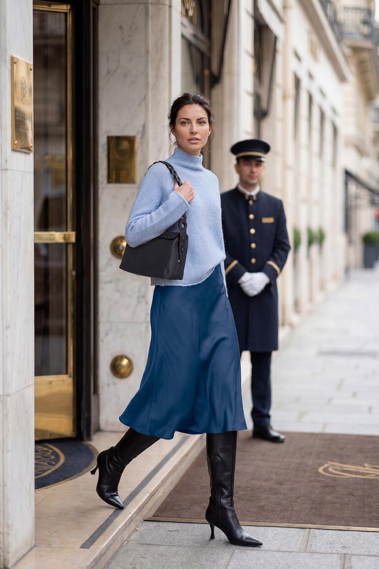 Femme en pull boxy Junghans 1954 sortant d'un hôtel