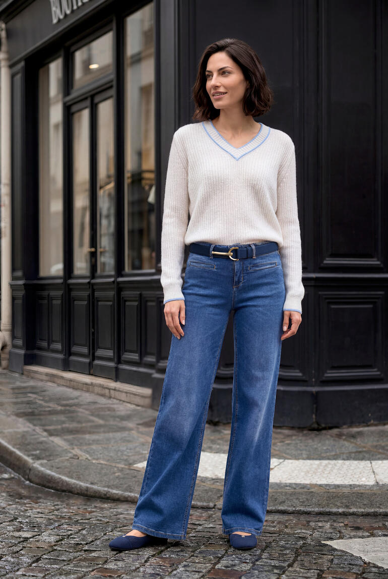 Femme en pull en cachemire et lin beige avec un jean bleu sur une rue